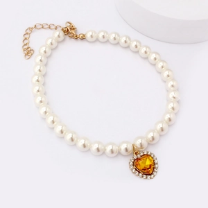 Detailed macro view of pet pearl necklace with a yellow heart gemstone pendant and gold clasp