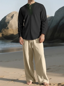 Detail of linen beach set featuring a black Henley shirt and beige trousers on the coast
