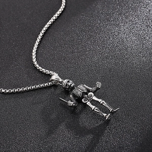 Close-up of a vintage steel skeleton pendant holding a sword with a box chain necklace