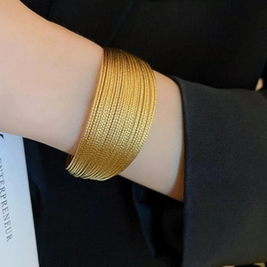 Detail of layered gold multi-strand wire cuff bracelet on model with black suit