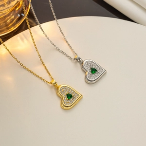 Detail of heart necklaces in gold and silver with emerald green zircon pendants