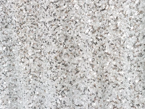Détail macro montrant la texture des paillettes argentées brillantes sur la robe