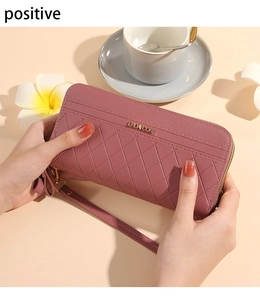 Detailed view of dusty pink quilted leather wallet with gold zipper and wrist strap