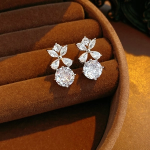 Vue détaillée des boucles d'oreilles fleurs en argent et zircons dans un écrin à bijoux