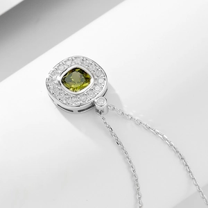 Macro shot of silver pendant with square olive green gemstone and white zircon halo