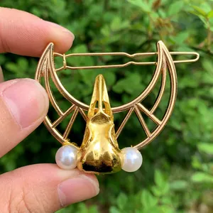 Detail of vintage gold raven skull hair clip with crescent moon and white pearls