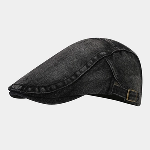 Detail view of washed black denim ivy cap with vintage texture and brass side buckle