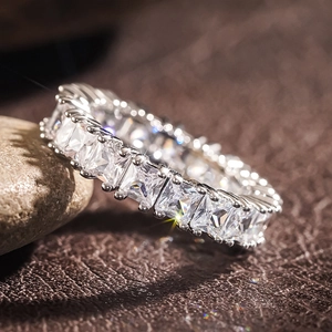 Macro shot of silver eternity ring with square-cut zircons set on a pebble stone