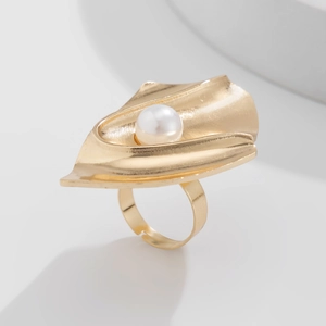 Detail of a gold metallic ring with a crushed texture and central pearl on white background