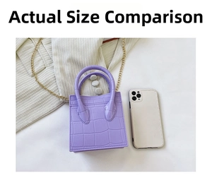 Macro detail of purple crocodile pattern mini bag with gold chain next to a phone for scale