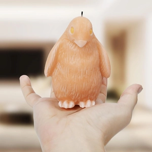 Nahaufnahme einer handgemachten Pinguin-Kerze mit orangebrauner Textur und Kerzendocht