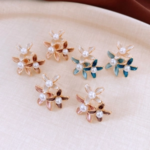 Detailed macro view of 18K gold plated flower earrings with elegant pearls and enamel petals