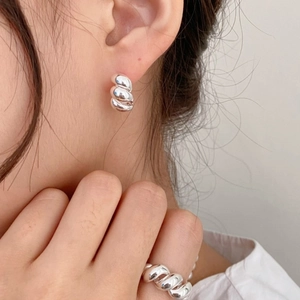 Detail of twisted silver earrings and matching ring on model for minimalist style