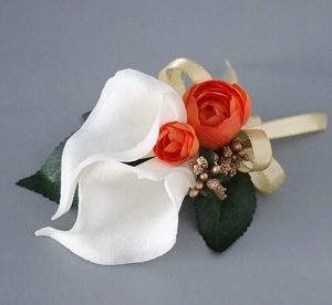 Close-up of white calla lily and orange roses boutonniere with gold ribbon details
