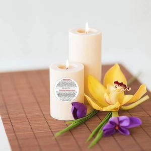 Pillar candles with circular safety warning labels on bamboo mat with floral decor