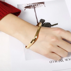Women's minimalist gold titanium steel square bangle with polished faceted finish