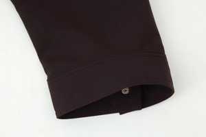 Close-up of dark brown jacket cuff showing silver snap button and detailed stitching