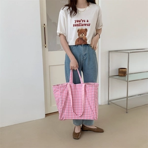 Pink and white checkered canvas tote bag shown on model in a modern lifestyle setting