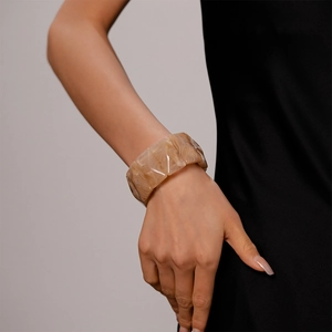Detail of vintage beige marble textured acrylic wide bangle with geometric facets