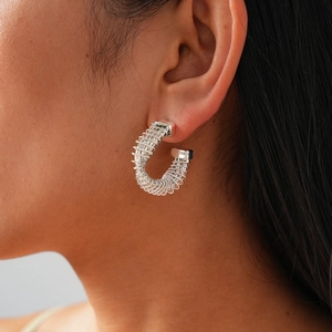 Close-up of a silver twisted spiral hoop earring worn by a model in a lifestyle shot