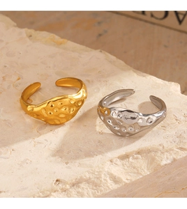 Detail of gold and silver hammered stainless steel open rings on travertine stone