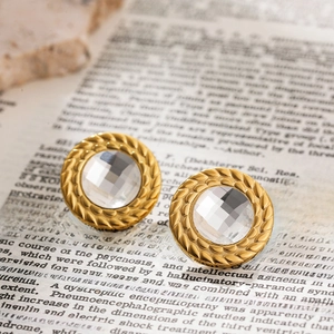 Detail of vintage 18K gold-plated earring with center crystal on old newspaper backdrop