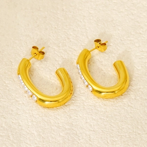 Elegant gold U-shaped hoop earrings with a row of small white pearls on textured background