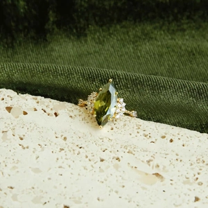 Detailed close-up of 14k gold plated ring with oval green zircon and side diamonds