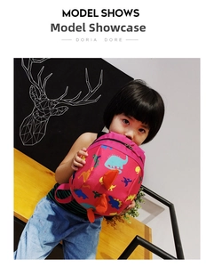 Close-up of rose pink kids backpack with colorful cartoon dinosaur prints and side fins