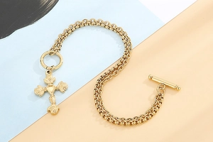 Detail of gold double-layer chain bracelet featuring a rose cross and OT toggle clasp