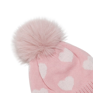 Detail der rosa Strickmütze mit weißen Herzmustern und einem flauschigen Bommel oben