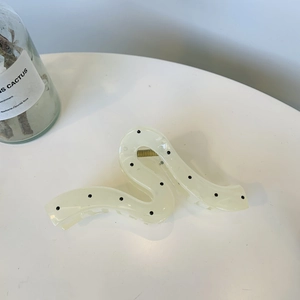 Elegant beige polka dot hair claw clip with sleek snake design on a minimalist white surface