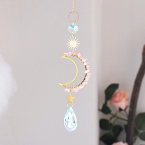 Detailed close-up of crescent moon pendant with pink crystal stones and faceted glass ball