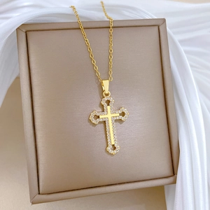 Macro shot of gold cross necklace with sparkling crystals on silk background
