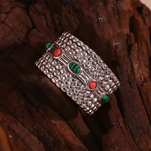 Detailed macro of vintage silver ring with red agate and green malachite stones on wood