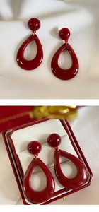 Detail view of red resin teardrop earrings with marble texture in a jewelry box display