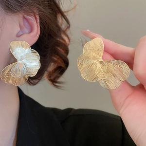 Détail de grandes boucles d'oreilles pétales bicolores en maille de métal argenté et doré