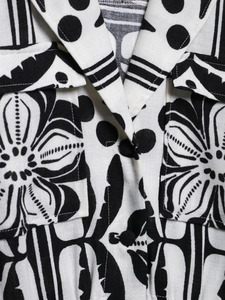 Detailed view of Cuban collar and buttoned pockets on printed black and white romper