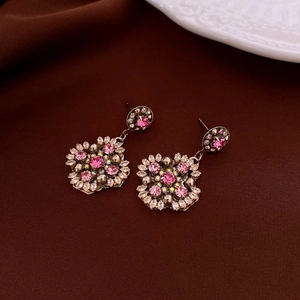 Detail of vintage gold-plated earrings with pink gemstones and iridescent crystals