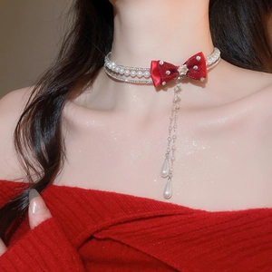 Detail of red bow pearl choker with star pendant and cascading drop tassel on model
