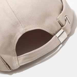 Close-up of adjustable metal buckle and stitching on beige cotton brimless docker hat