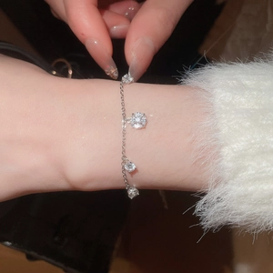 Close-up of a silver zircon charm bracelet with sparkling round stones on a thin chain