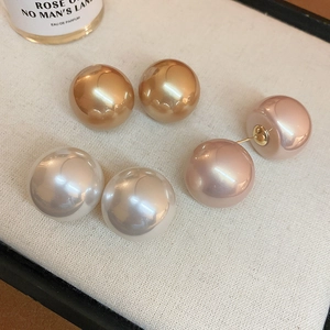Dettaglio macro di orecchini a perla oversize nei colori marrone oro, rosa e bianco