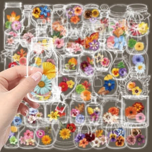 Hand placing transparent floral bottle stickers with colorful daisies and sunflowers