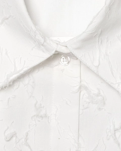 Détail macro du col de chemise blanche présentant une texture à franges type plumes