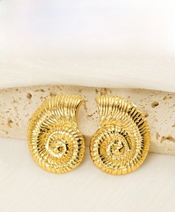 Detailed macro view of gold conch shell earrings with spiral texture on white silk fabric