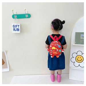 Rear view of a child wearing the red dinosaur print backpack in a cozy home setting