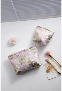 Détail du lot de trousses à maquillage jacquard fleuri avec broderie dorée et logo