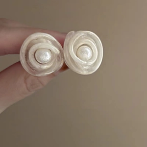 Close-up of pearl flower earrings with spiral petals held for detailed texture display