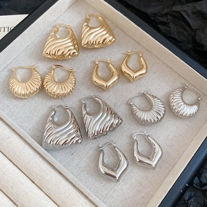 Macro shot of assorted gold and silver polished metal earrings on a linen tray
